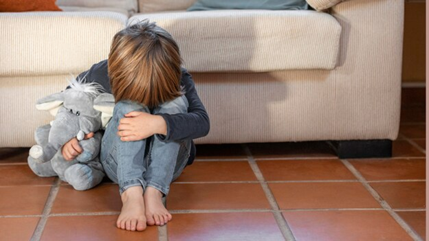 image of a boy holding stuffed toy, head down in discouraged manner.